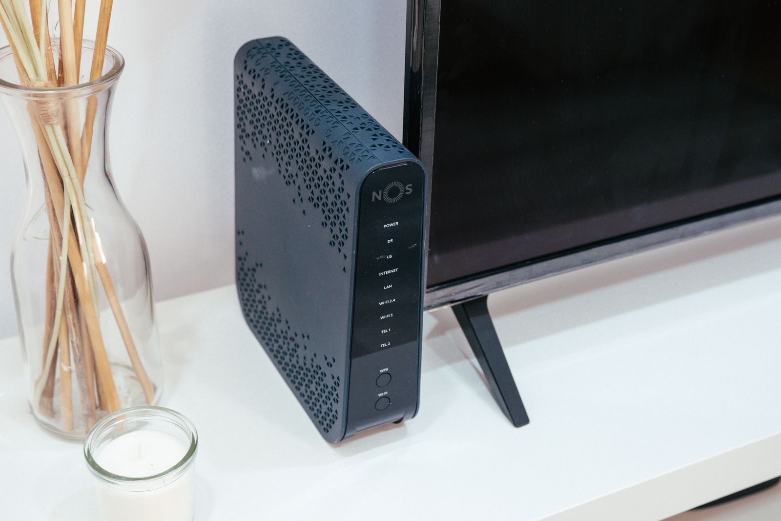 Çalışma masasında monitörün yanında duran ev tipi modem